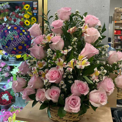 Tall basket arrangement of pink roses with white daisies, alstroemeria, and a small birthday balloon