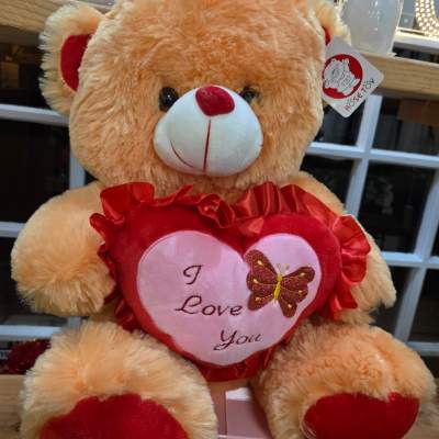 Plush teddy bear holding a heart with "I Love You" text