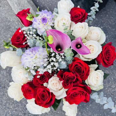 Round bouquet of red and white roses with pink calla lilies and pale lavender blooms