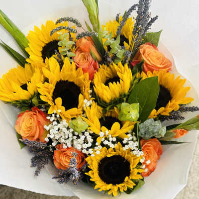 Bouquet of yellow sunflowers, orange roses, and white filler flowers wrapped in white paper