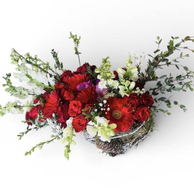Low arrangement of red roses and gerbera daisies with white flowers in a rustic basket container