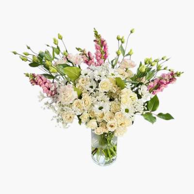 Tall vase arrangement with cream roses, white daisies, and pink snapdragons in a clear glass cylinder