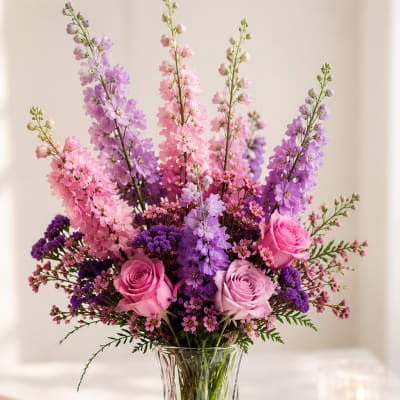 Pink and purple flowers arranged in a clear glass vase
