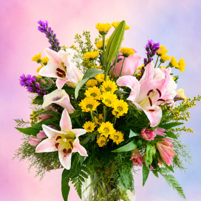 Bouquet of pink lilies and yellow daisies in a clear glass vase