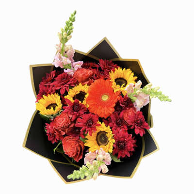 Bright bouquet of orange gerbera, yellow sunflowers, red mums, and roses in black and gold wrap