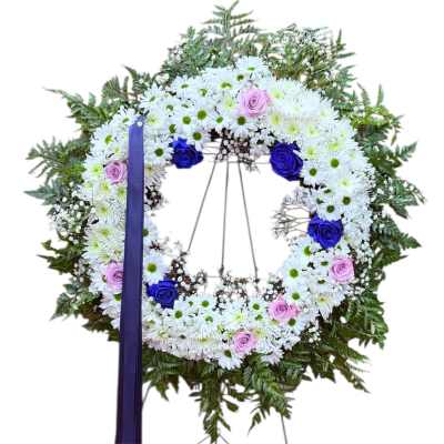 Standing wreath of white daisies with blue and pink roses on a metal easel with ribbon