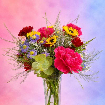 Mixed bouquet of bright flowers in a clear glass vase