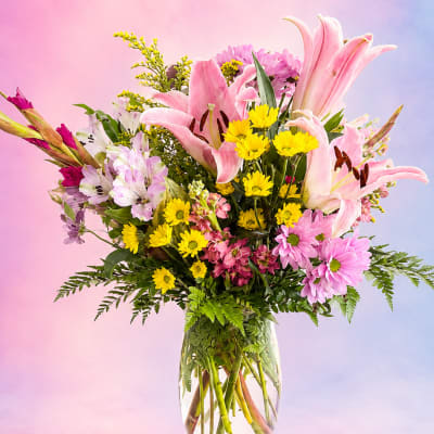Pink lilies and yellow daisies in a clear glass vase