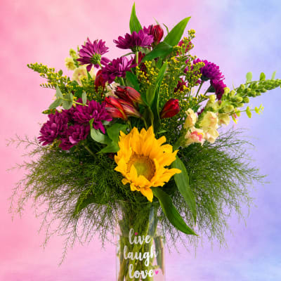 Mixed bouquet with sunflowers, purple chrysanthemums, and red alstroemeria in a glass vase