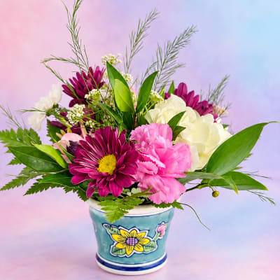Pink and white flowers arranged in a decorative ceramic pot