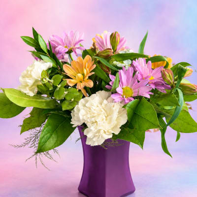 Mixed bouquet of pink, peach, and white flowers in a purple vase