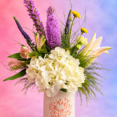 Mixed bouquet in a ceramic vase with white hydrangeas, purple spikes, and yellow blooms