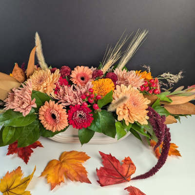 Autumn floral arrangement with peach and pink blooms in a white container
