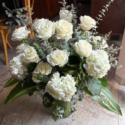 White roses and hydrangeas arranged in a glass vase