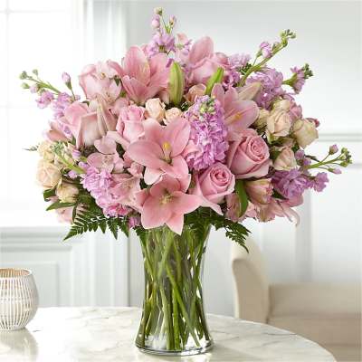 Pink lilies and roses arranged in a clear glass vase