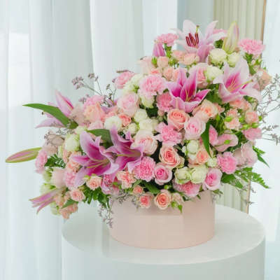 Pink and white floral arrangement in a round box