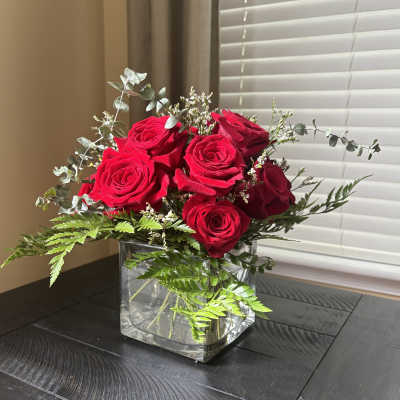 Red roses arranged in a clear square glass vase