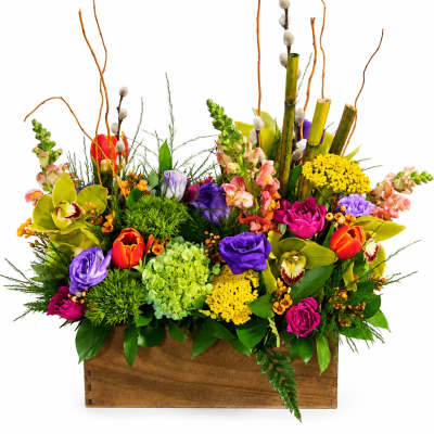 Colorful mixed flower arrangement in a wooden box with tall branches