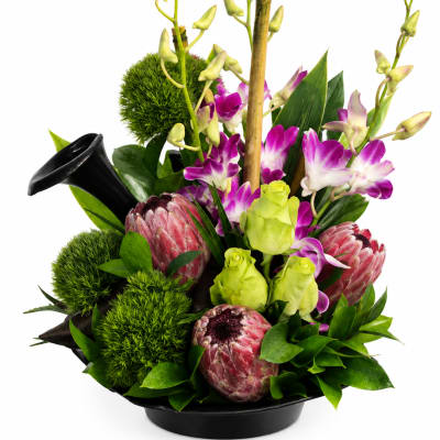 Tropical bouquet with purple orchids and pink protea in a black vase