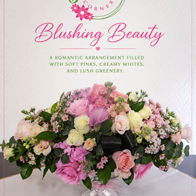Pink and white floral arrangement in a clear pedestal vase