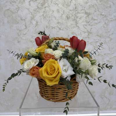 Basket of mixed roses with red tulips and greenery