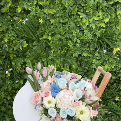 Pastel bouquet of roses, tulips, and peonies in a white cart