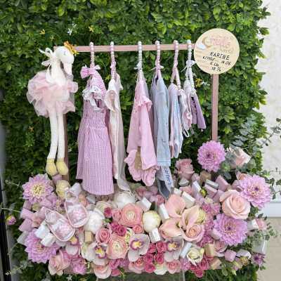 Pink baby gift display with flowers, clothes, and a plush bunny