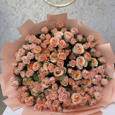 Large bouquet of peach and blush roses wrapped in pink paper