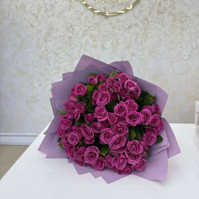 Bouquet of bright pink roses wrapped in lavender paper