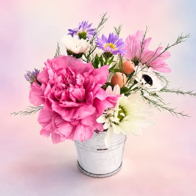 Pink and white flowers arranged in a small metal bucket