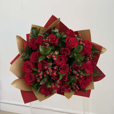 Bouquet of red roses with berries and greenery in red and gold wrap
