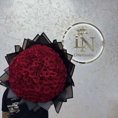 Large round bouquet of red roses wrapped in black paper