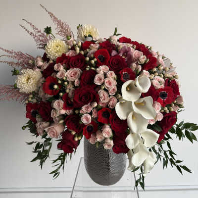 Large bouquet of red and blush roses with white calla lilies in a gray vase