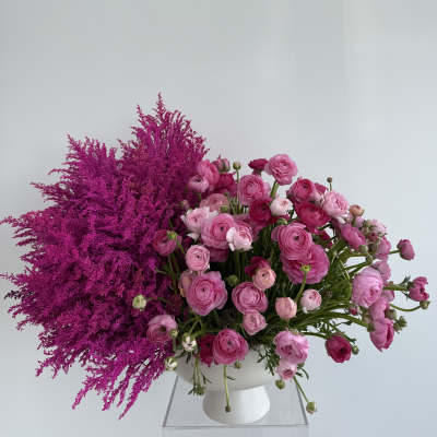 Pink ranunculus arrangement in a white vase with magenta filler