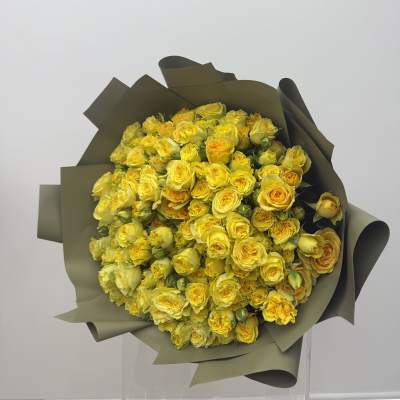 Large bouquet of yellow roses wrapped in dark paper