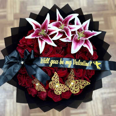 Bouquet of red roses topped with pink-and-white lilies and a black ribbon