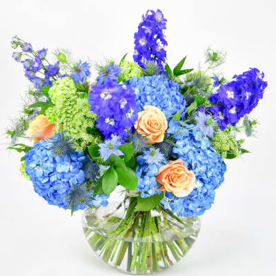 Blue and peach flower arrangement in a clear glass vase