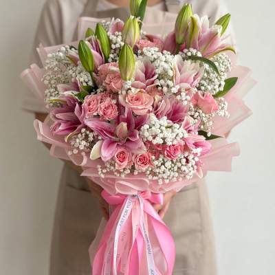 Pink lilies and roses bouquet wrapped in pink paper with a ribbon