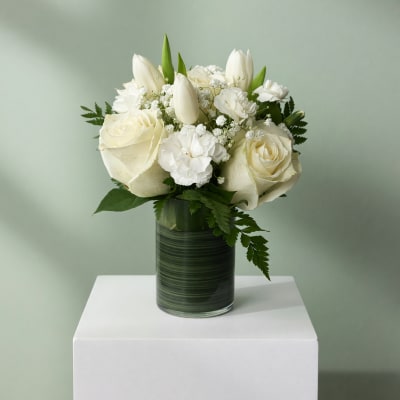 White roses and tulips arranged in a glass vase