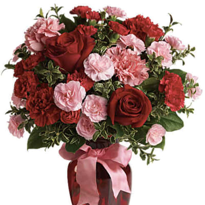 Red roses and pink carnations in a red vase with a pink ribbon