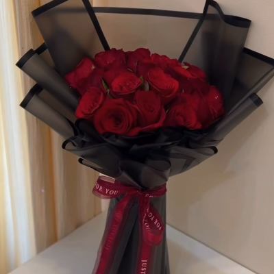 Bouquet of red roses wrapped in black paper with a red ribbon