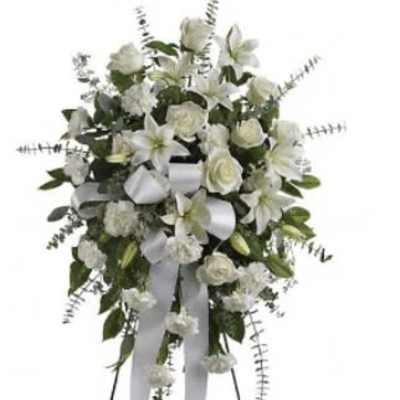 White floral standing spray with ribbon streamers on a stand
