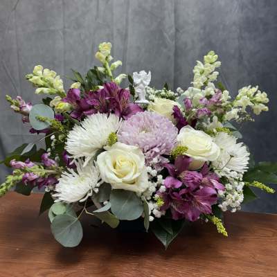 Mixed bouquet of white roses, purple flowers, and white daisies in a low container