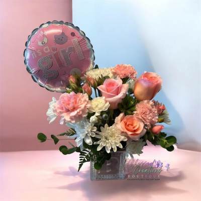 Pink and peach flower arrangement with a "It's a girl" balloon in a glass vase