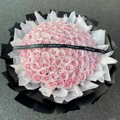 Large bouquet of pale pink roses wrapped in black and white paper