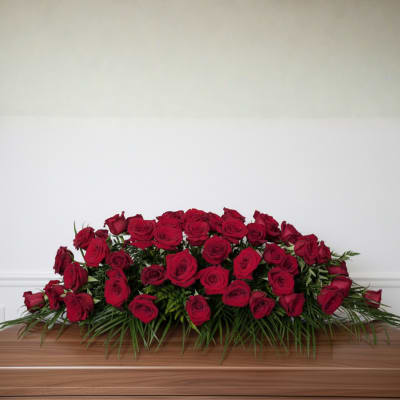 Low arrangement of red roses with greenery on a wooden surface