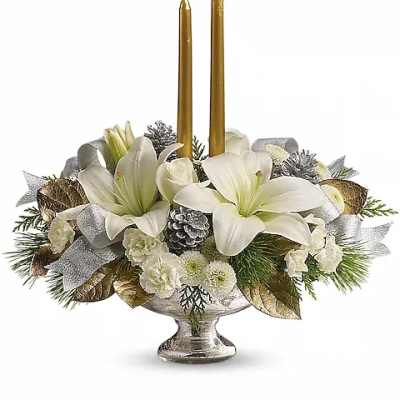White floral centerpiece with two gold taper candles in a silver pedestal bowl