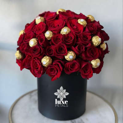 Red roses and gold-wrapped chocolates in a black box