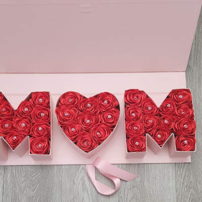 Heart-shaped rose box between two letter boxes with a pink ribbon