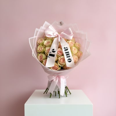 Bouquet of pale pink roses wrapped in pink paper with a satin bow